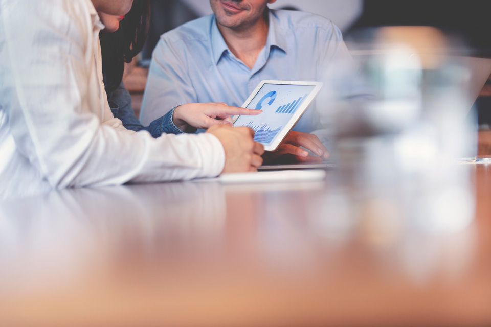 professionals interacting with tablet showing graphs